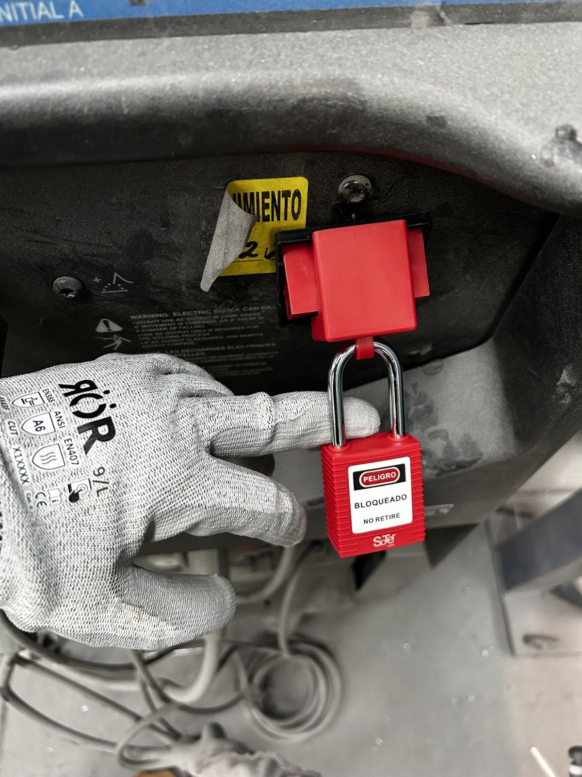Candado rojo de bloqueo con etiqueta de peligro instalado en el interruptor de una máquina