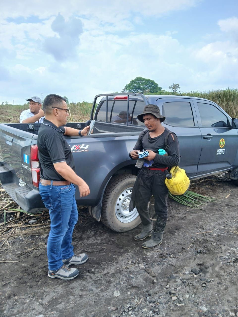 Roy Sosa revisando el equipo de protección de un trabajador agrícola junto a un cañal