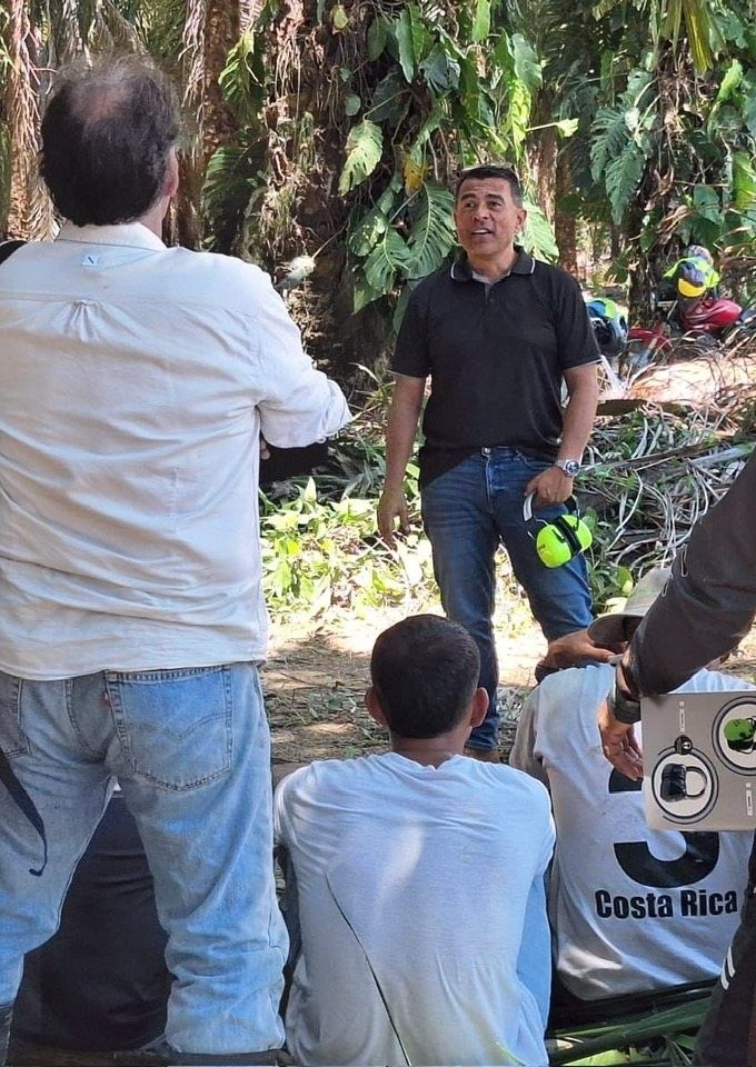 Roy Sosa explicando el uso de orejeras a trabajadores en una plantación